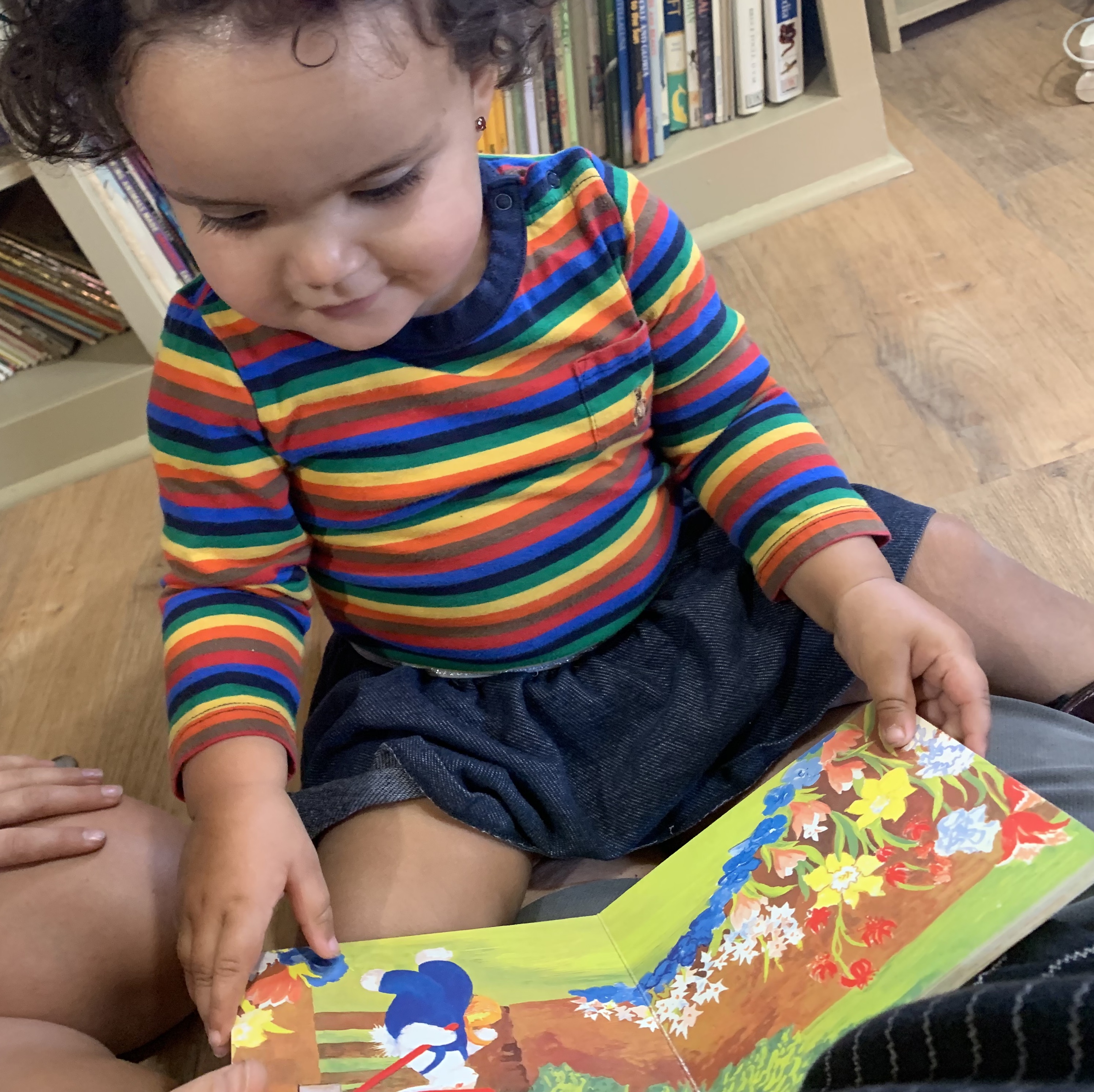 Small child with dark curly hair and striped shirt reading a book