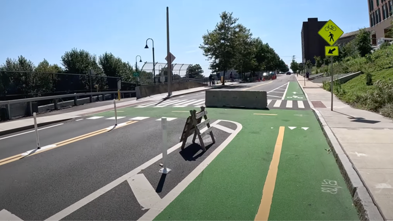 An intersection in Somerville with pedestrian walkway painted green, concrete barrier and flexi-posts for protection